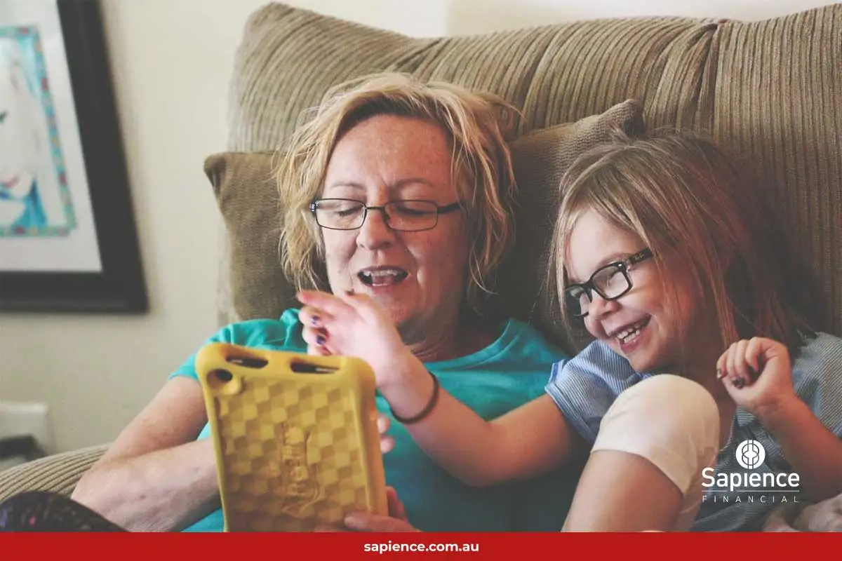 mother and daughter laughing and looking at tablet device
