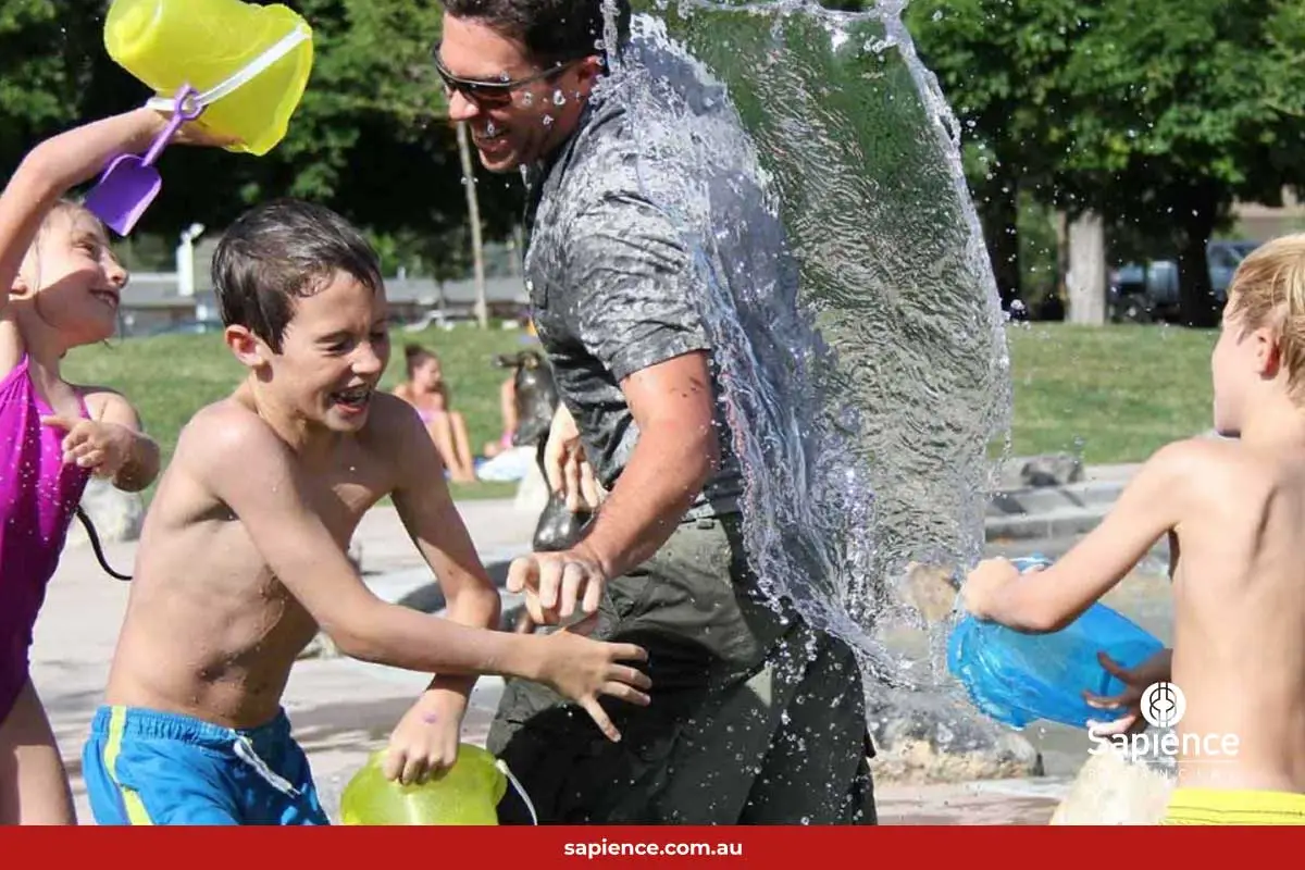 children and father having a playful water fight with buckets of water