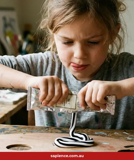 Creative little girl squeezing paid from a tube that is both black and white